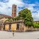 Pedestrians and bike riders taking a break to relax outside a medieval structure with a bell tower